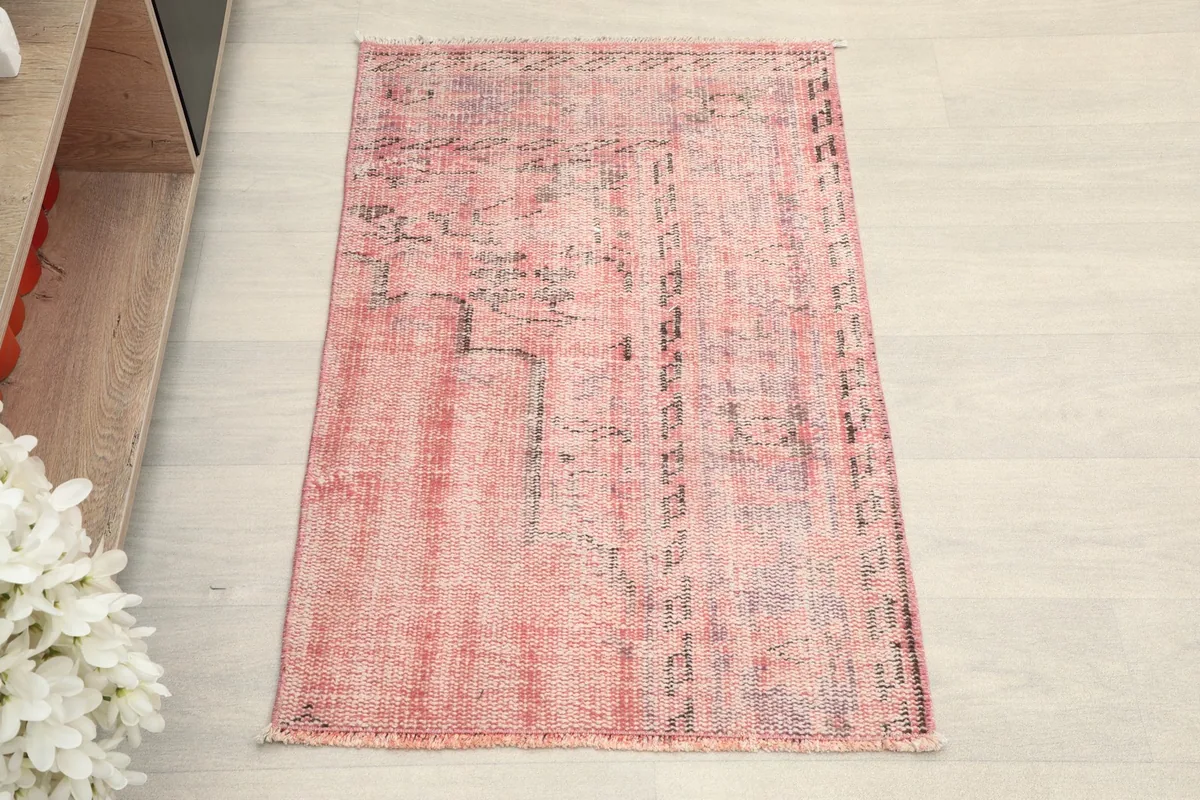 Overhead view of the small rose and pink vintage rug, showing its rectangular shape.