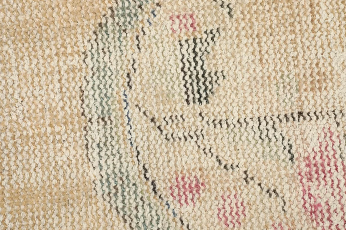 Close-up detail of the rug's upper section, showing rose and green motifs on the beige pile.