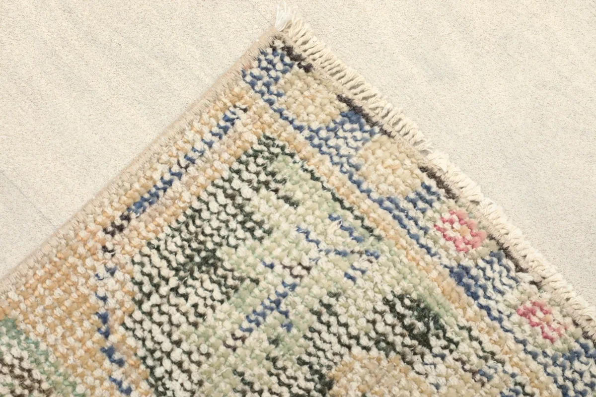 Close-up of a corner, revealing the blue and beige border and green tribal patterns.