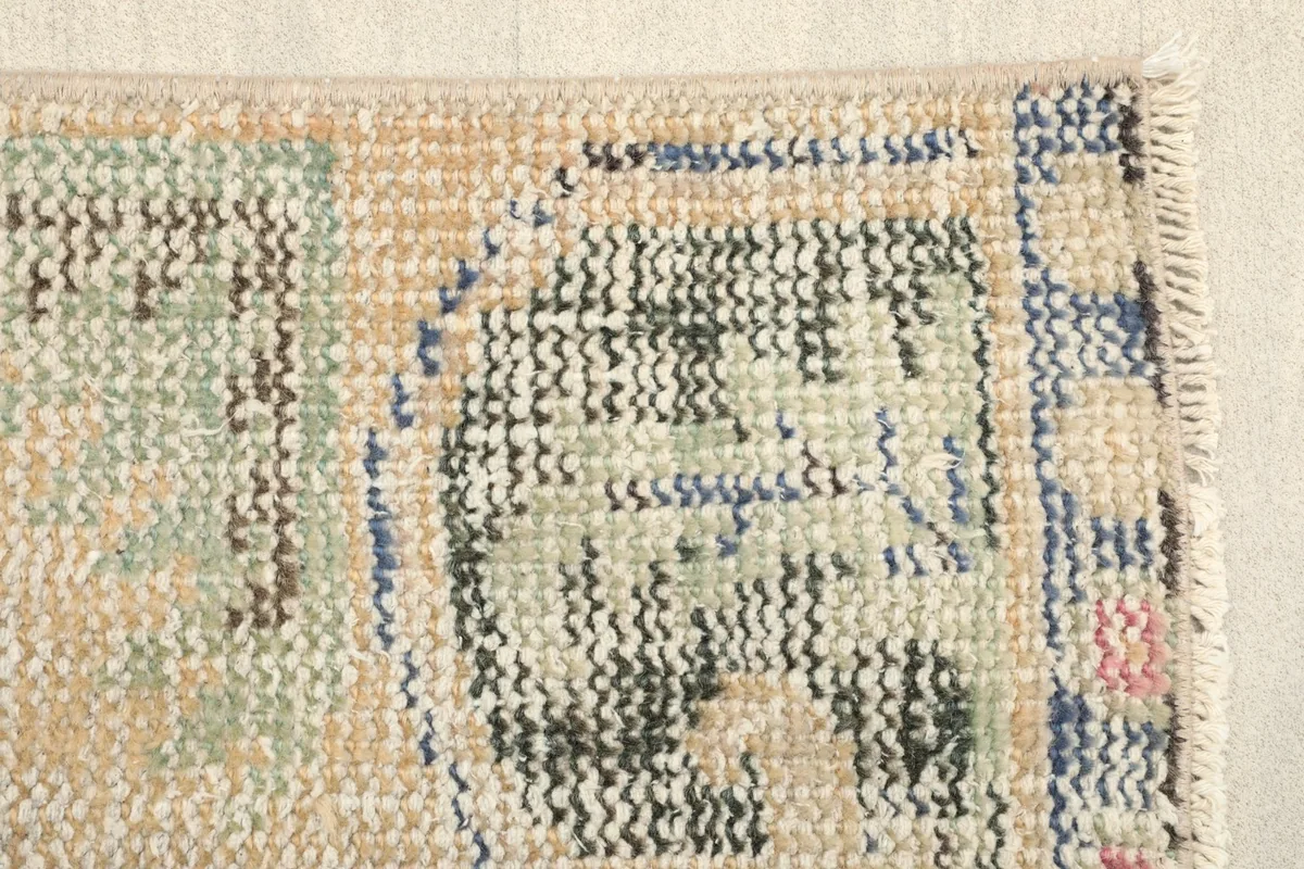 Detailed view of the rug's lower section, showcasing the dark green and blue geometric motifs.