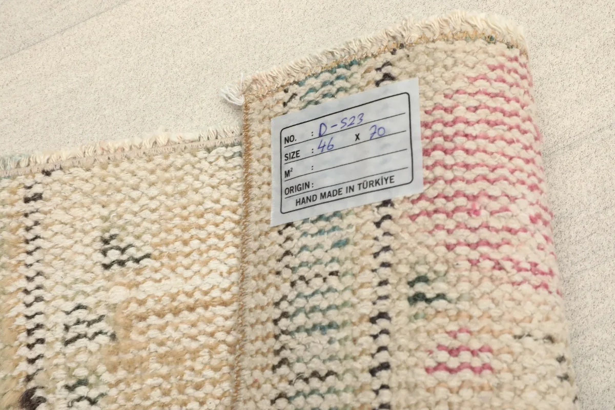 Close-up of the rug's back with a label, showing the tight hand-knotted weave and fringe.