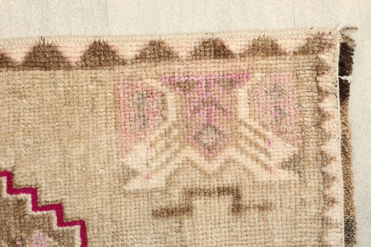 Close-up of the rug's border with brown geometric patterns and the beige main field.