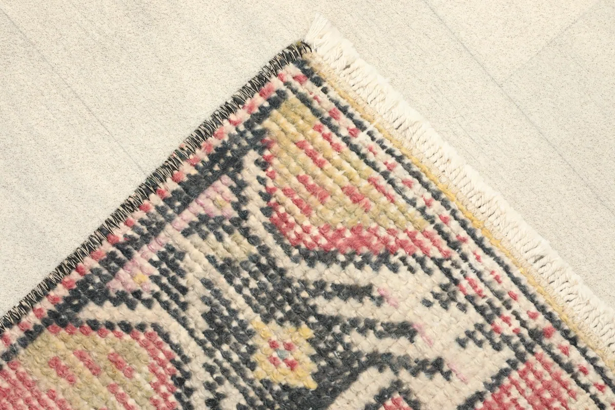 Corner view showing the faded rose field and black, yellow, ivory tribal patterns