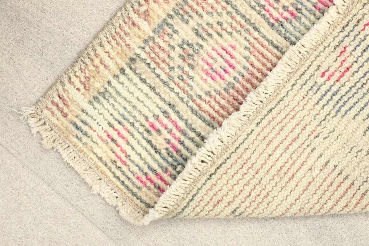 View of the rug folded to show the cotton foundation and reverse side