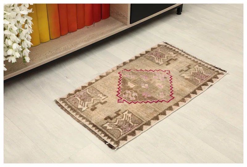 Full overhead view of the beige and rose tribal rug on a white background.