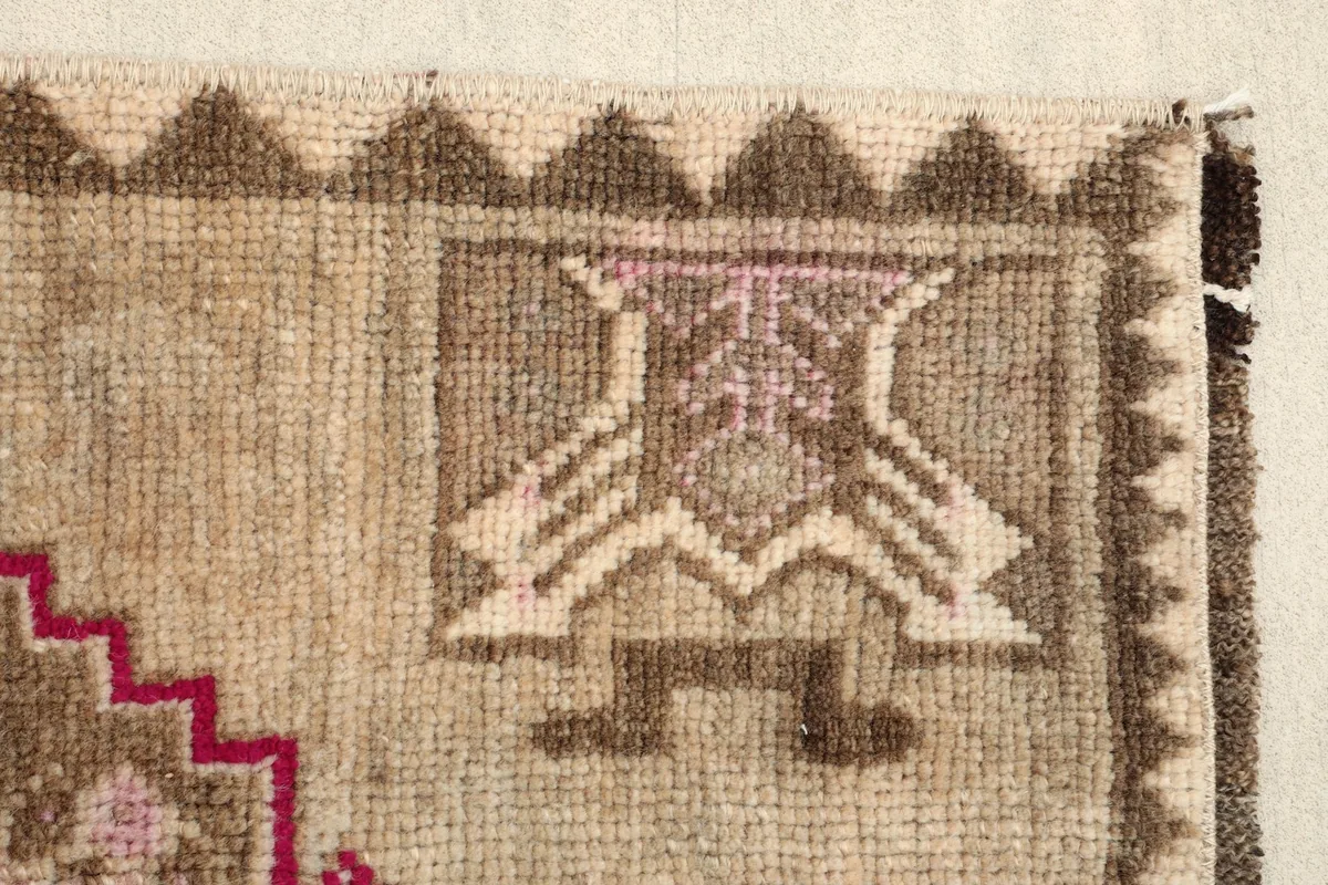 Close-up of a brown and beige tribal motif within the rug's border design.