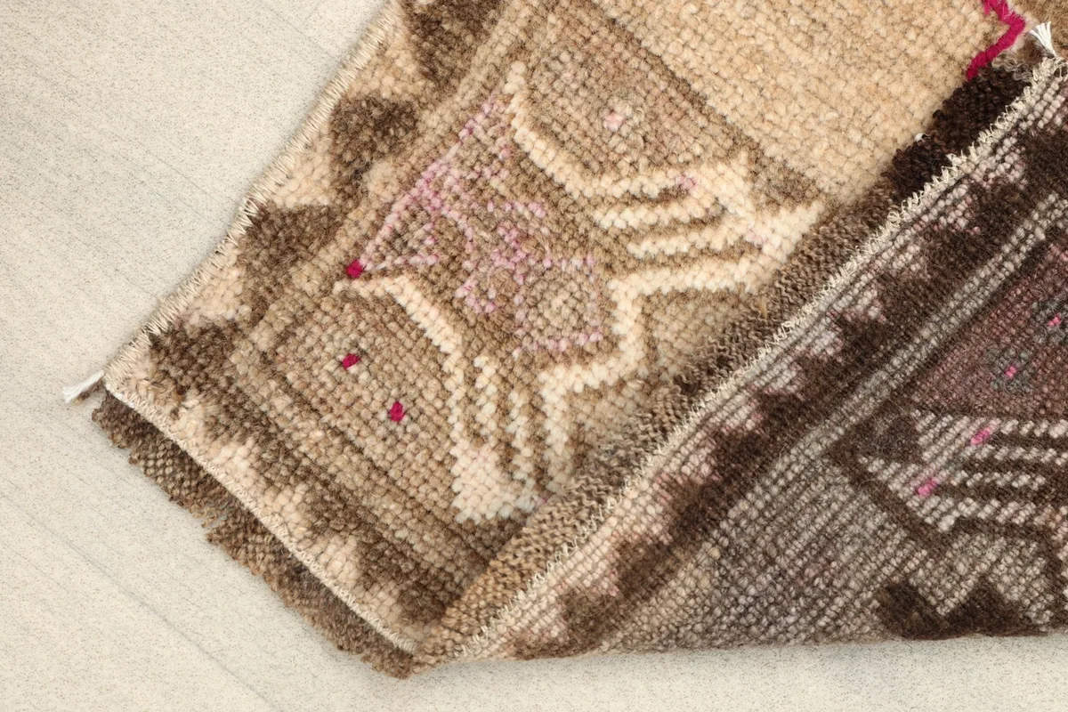 View of the rug's low pile and texture, with a folded corner.