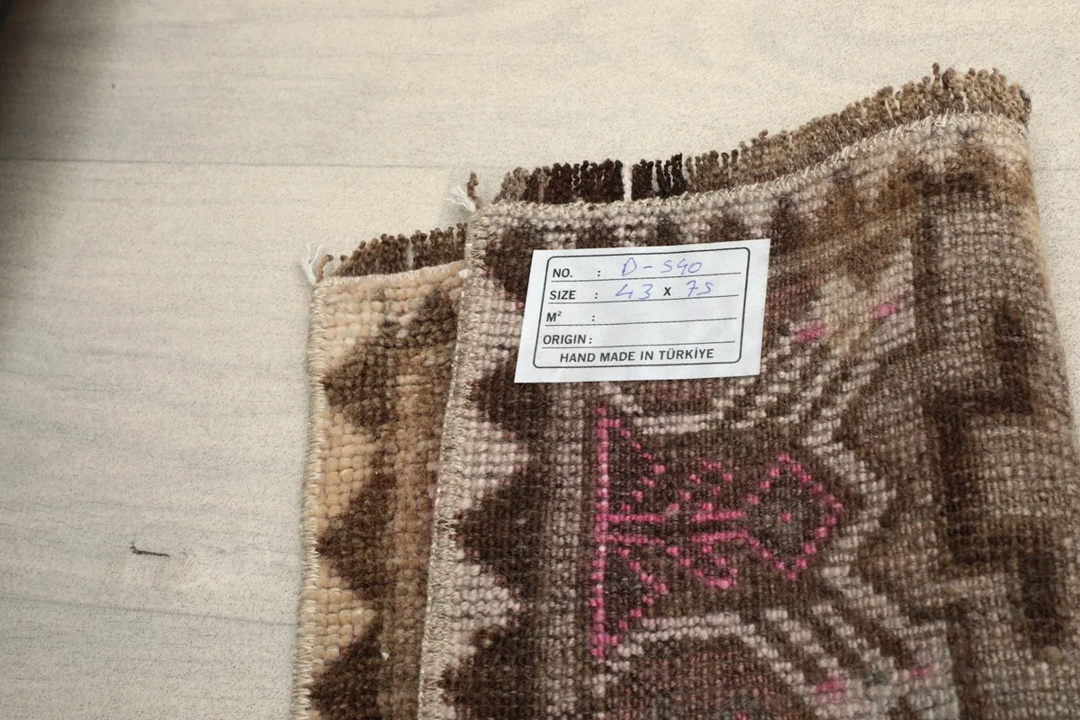 Close-up of the rug's reverse side, showing the hand-knotted cotton foundation and label.