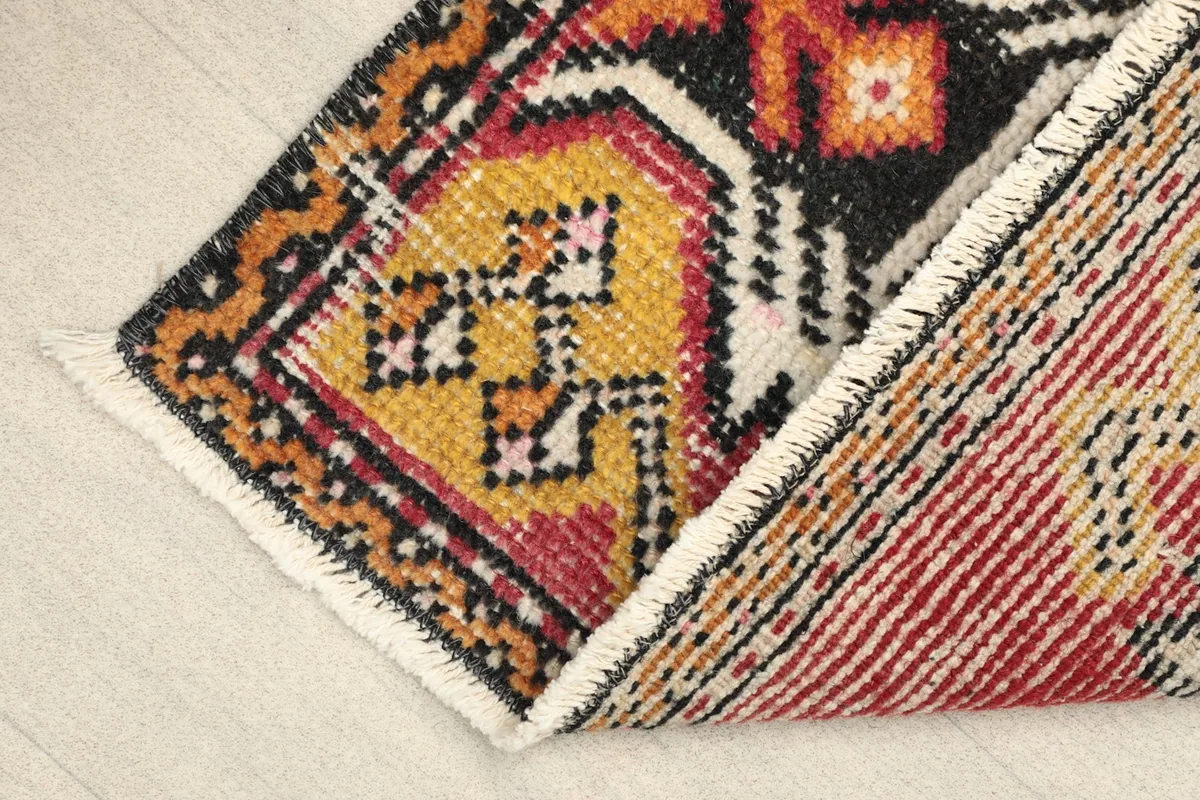 View of the rug's corner with the back visible, showing the cotton foundation and hand-knotting.