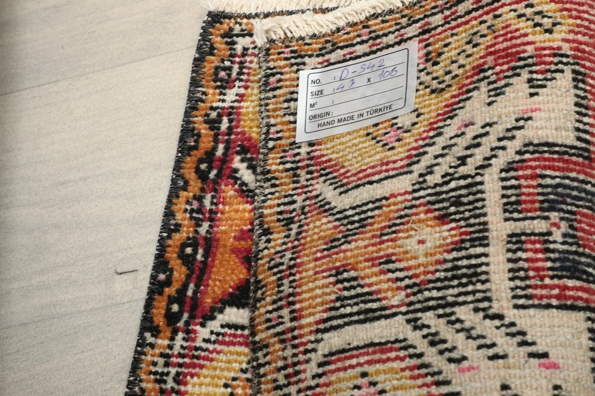 Close-up of the rug's back, displaying the hand-knotted structure and a label.