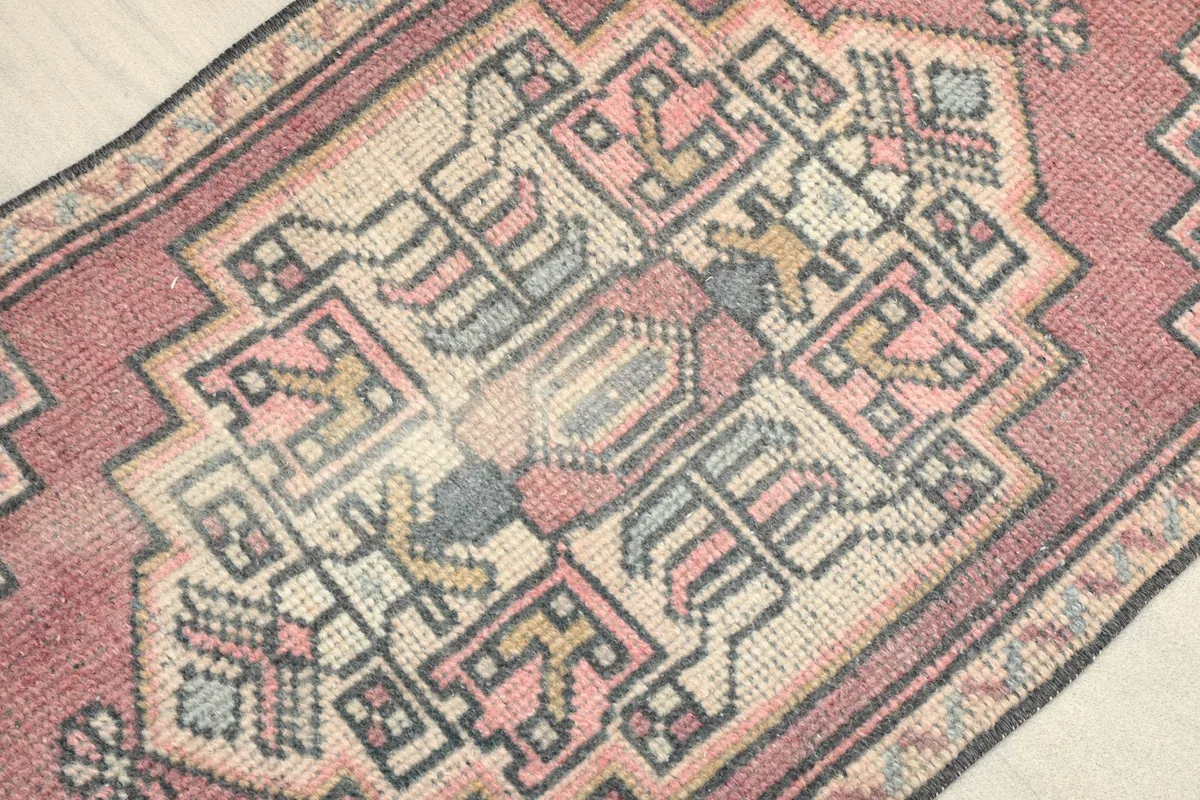 Close-up detail of the central tribal medallion and geometric patterns in rose, gray, and beige.