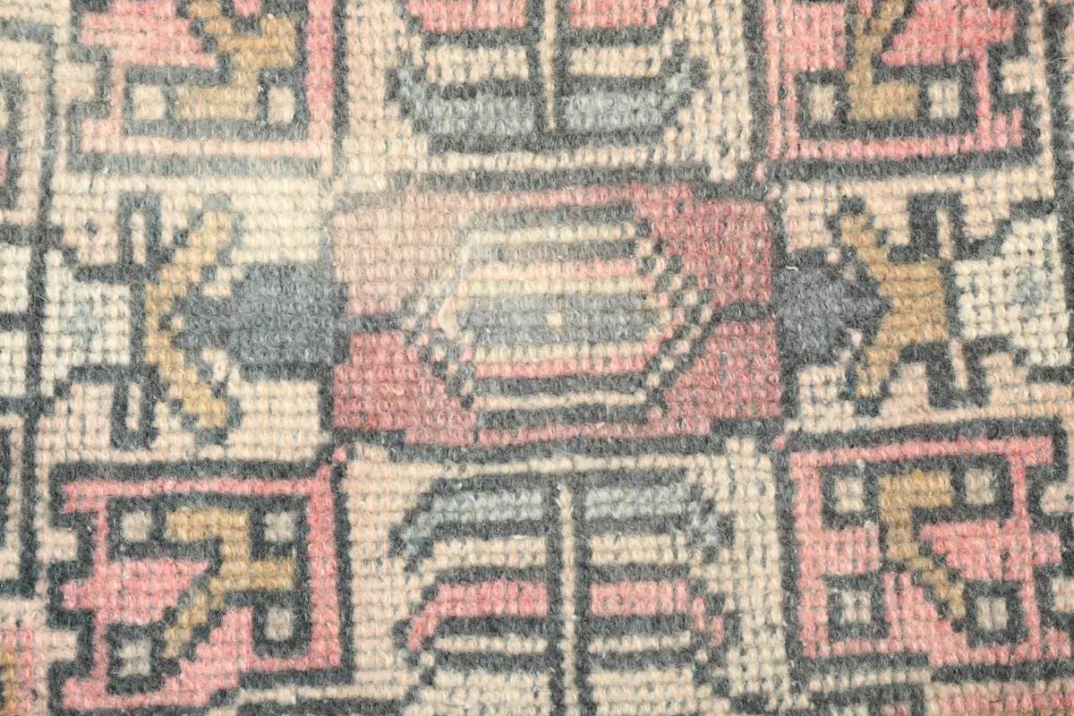 Macro detail showing the hand-knotted wool pile and intricate geometric motifs of the rug.