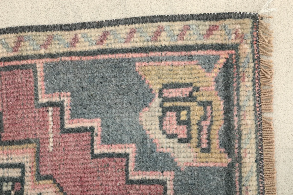 Side view of the rug's border, showing the transition from the rose field to the gray geometric edge.
