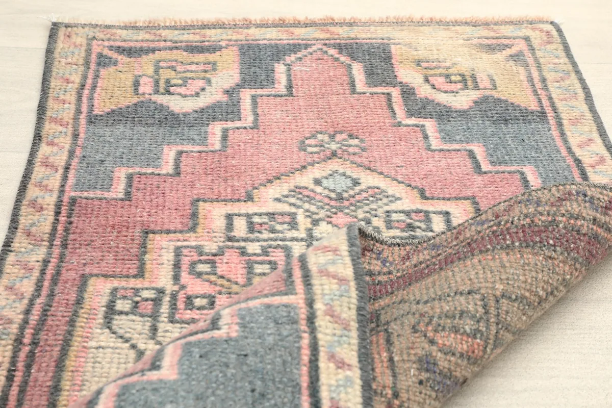 Partial fold of the rug, displaying the back of the hand-knotted construction and fringe.
