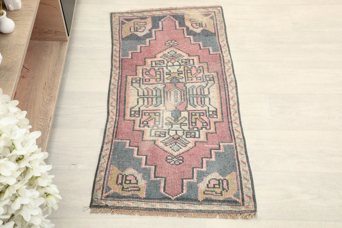 Overhead view of the rose and gray tribal rug, showcasing its full design and colors.