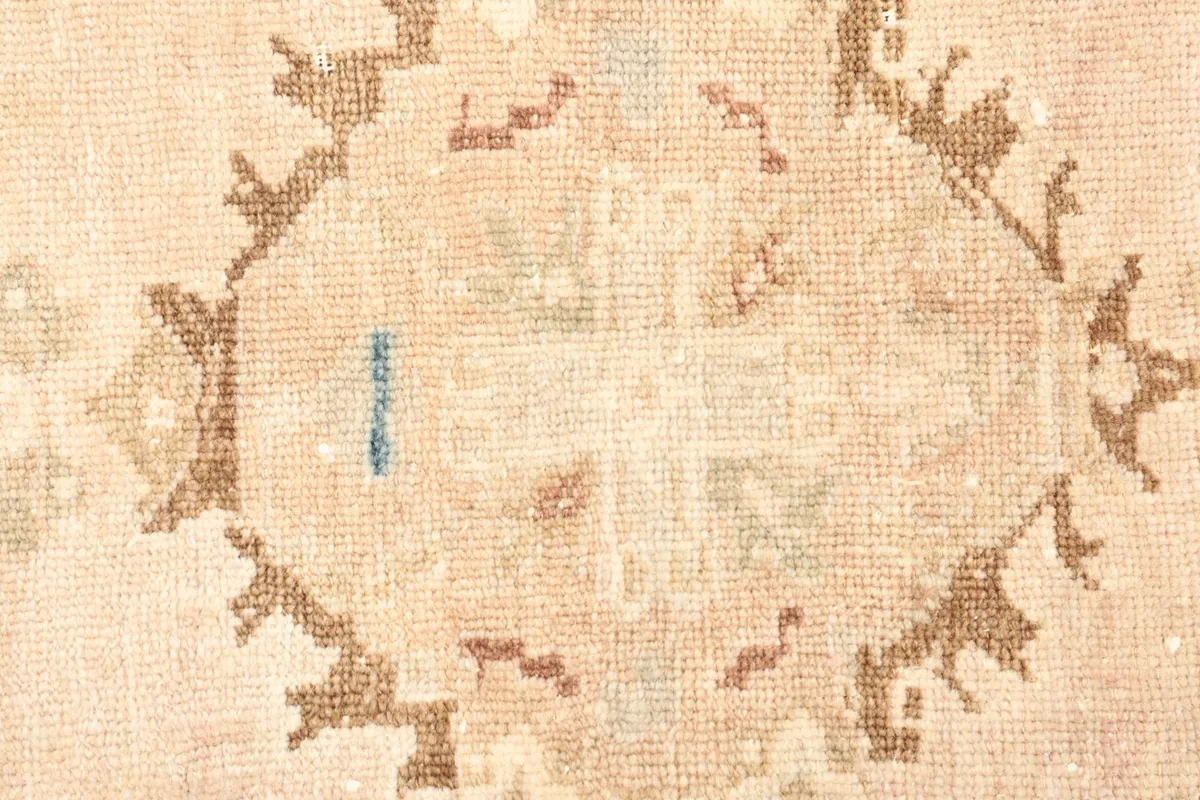 Close-up detail of the central geometric medallion with beige, rust, and blue threads
