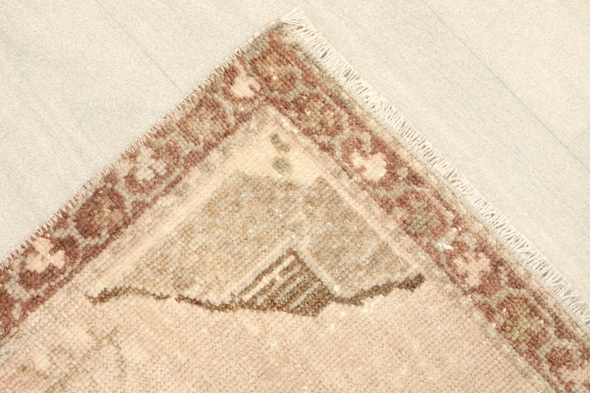 Corner detail showing the rust and brown patterned border and a glimpse of the fringe