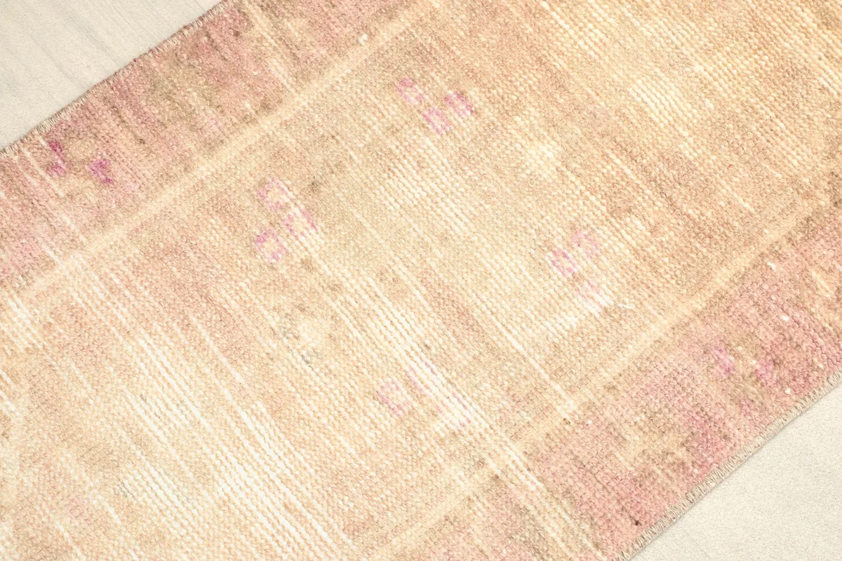 Close-up detail of the vintage wool pile, showing the natural wear and blend of pink and beige threads.