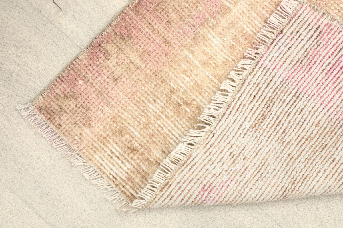 View of the back of the rug, folded to show the hand-knotted cotton foundation and wool pile construction.