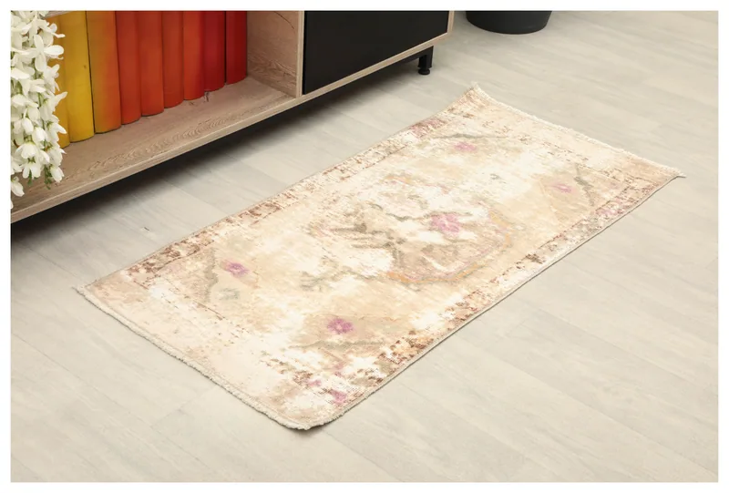 Full top view of the 1'9" x 3'9" beige and pink vintage Anatolian rug on a light floor.