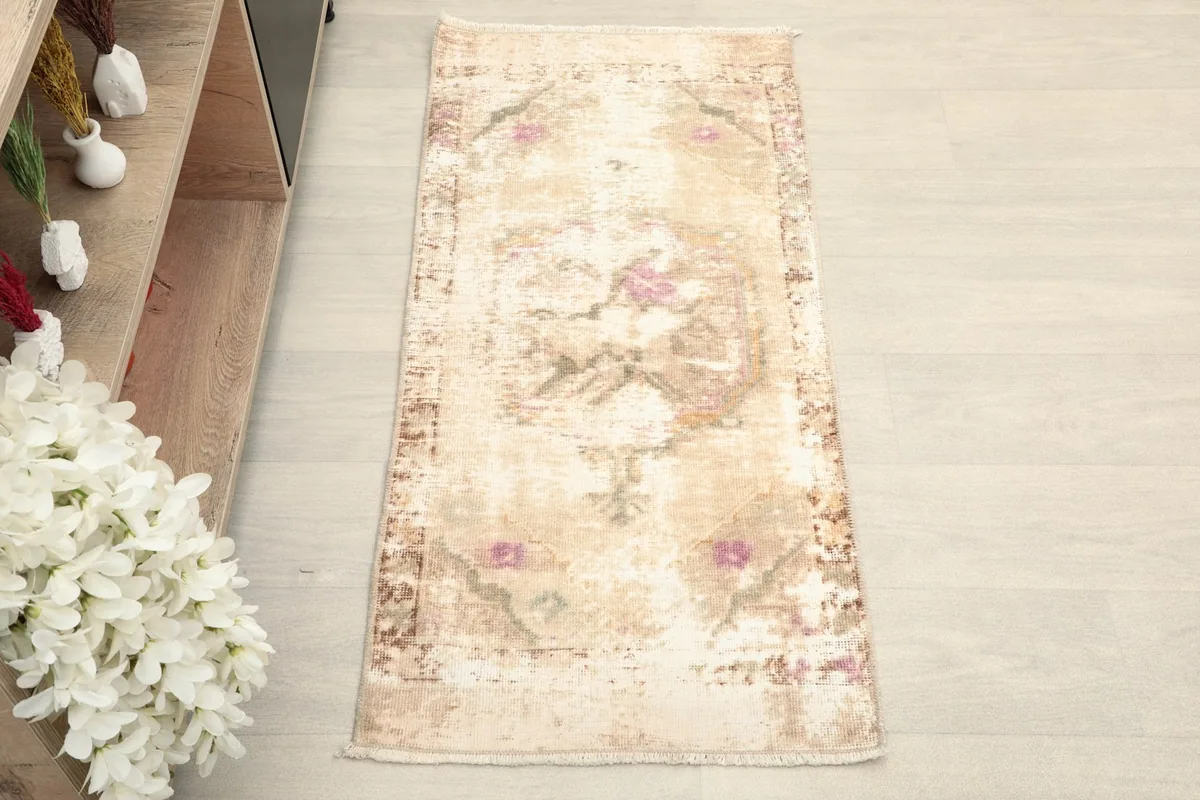 Overhead view showcasing the full length and width of the distressed beige vintage rug.