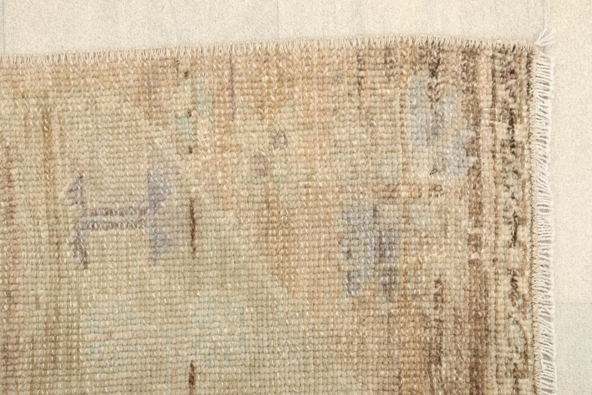 Close-up of the rug's border area, highlighting the faded brown and purple accents.
