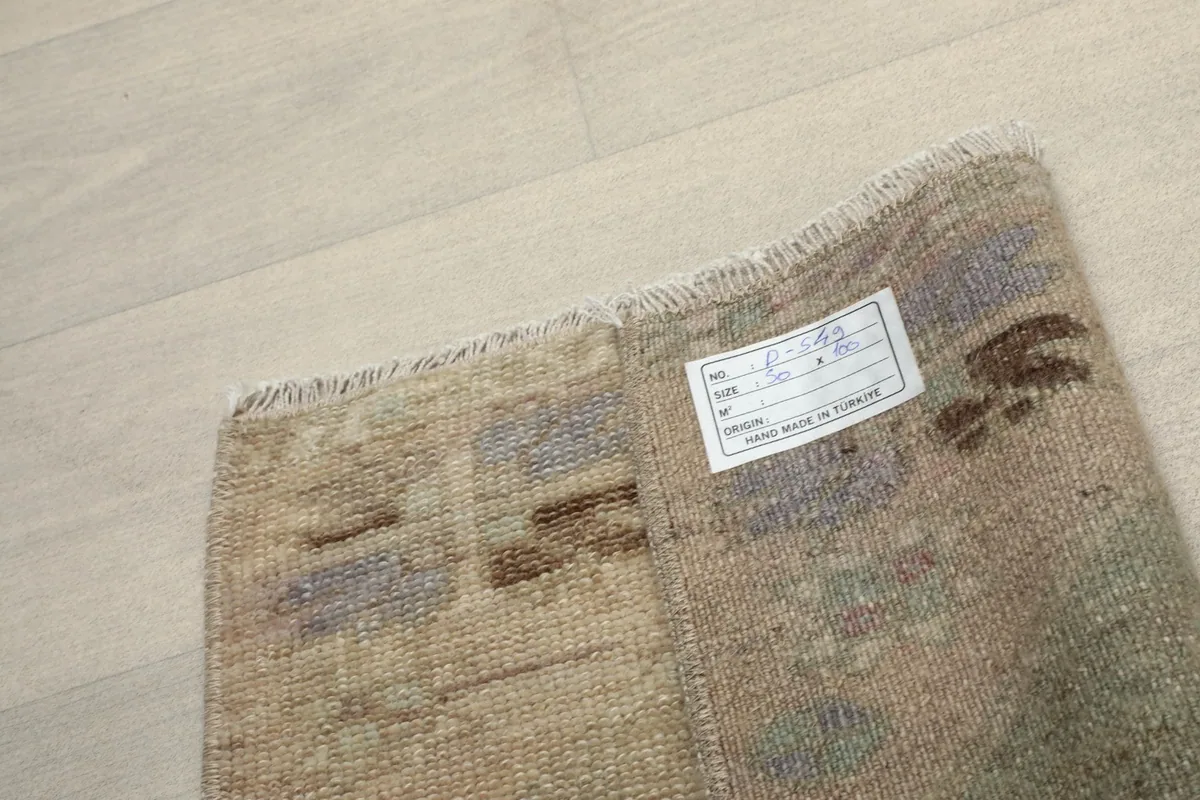 Underside of the hand-knotted rug, revealing the cotton foundation and a product tag.