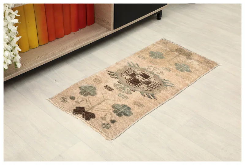 Full top view of the beige tribal medallion rug on a light floor, next to a shelf.