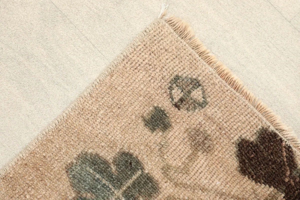 Detail of the upper corner, showing the beige field and subtle motif elements.