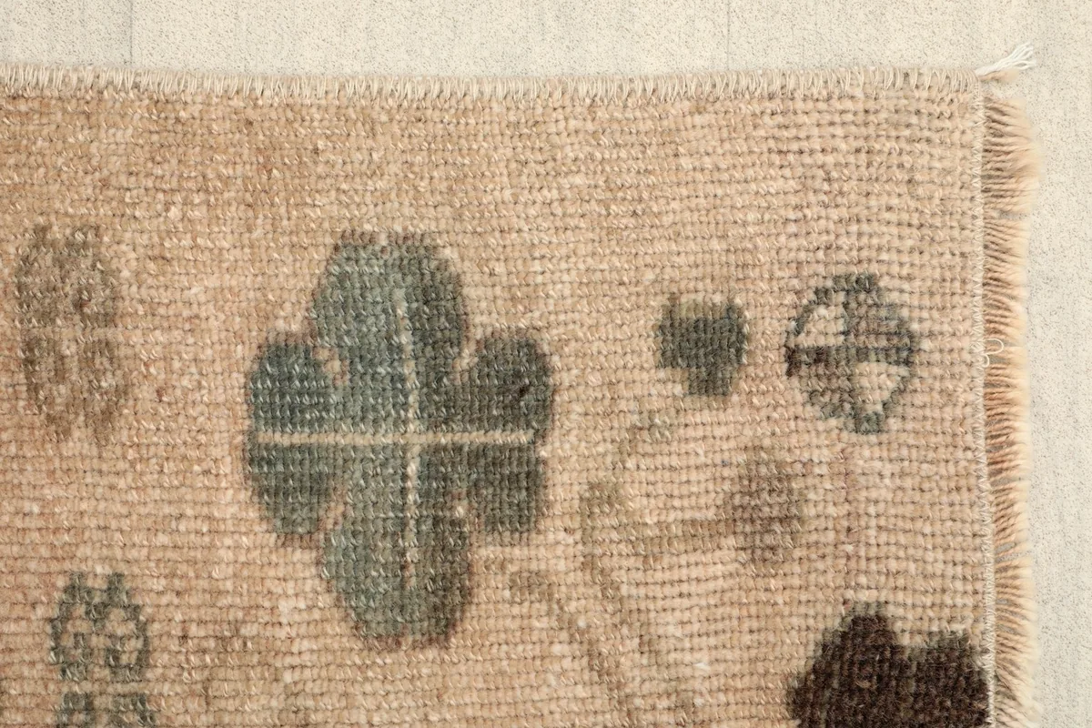 Close-up of the side edge and a stylized green motif on the beige background.