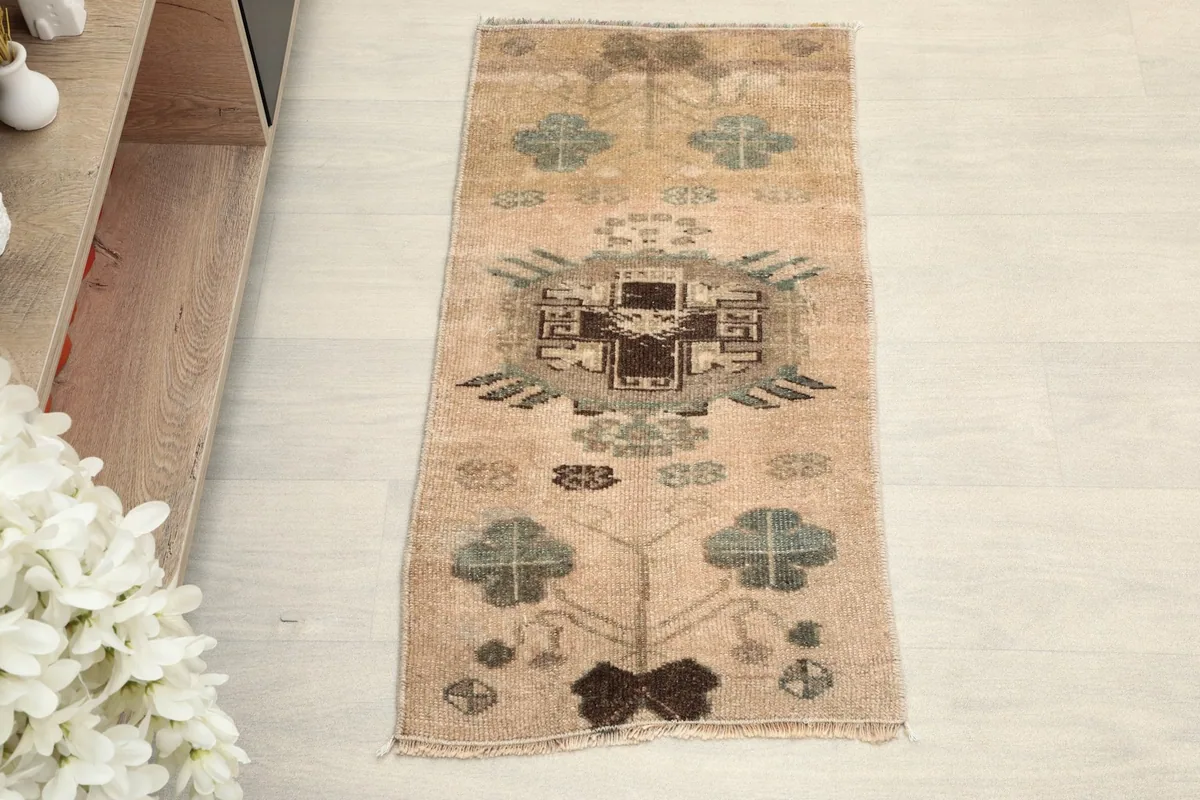 Overhead view of the beige doormat, showing the central geometric and surrounding motifs.