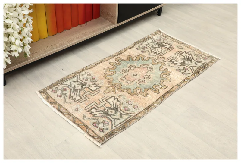 Full top view of the beige and blue medallion tribal rug on a white background, placed near a bookshelf.