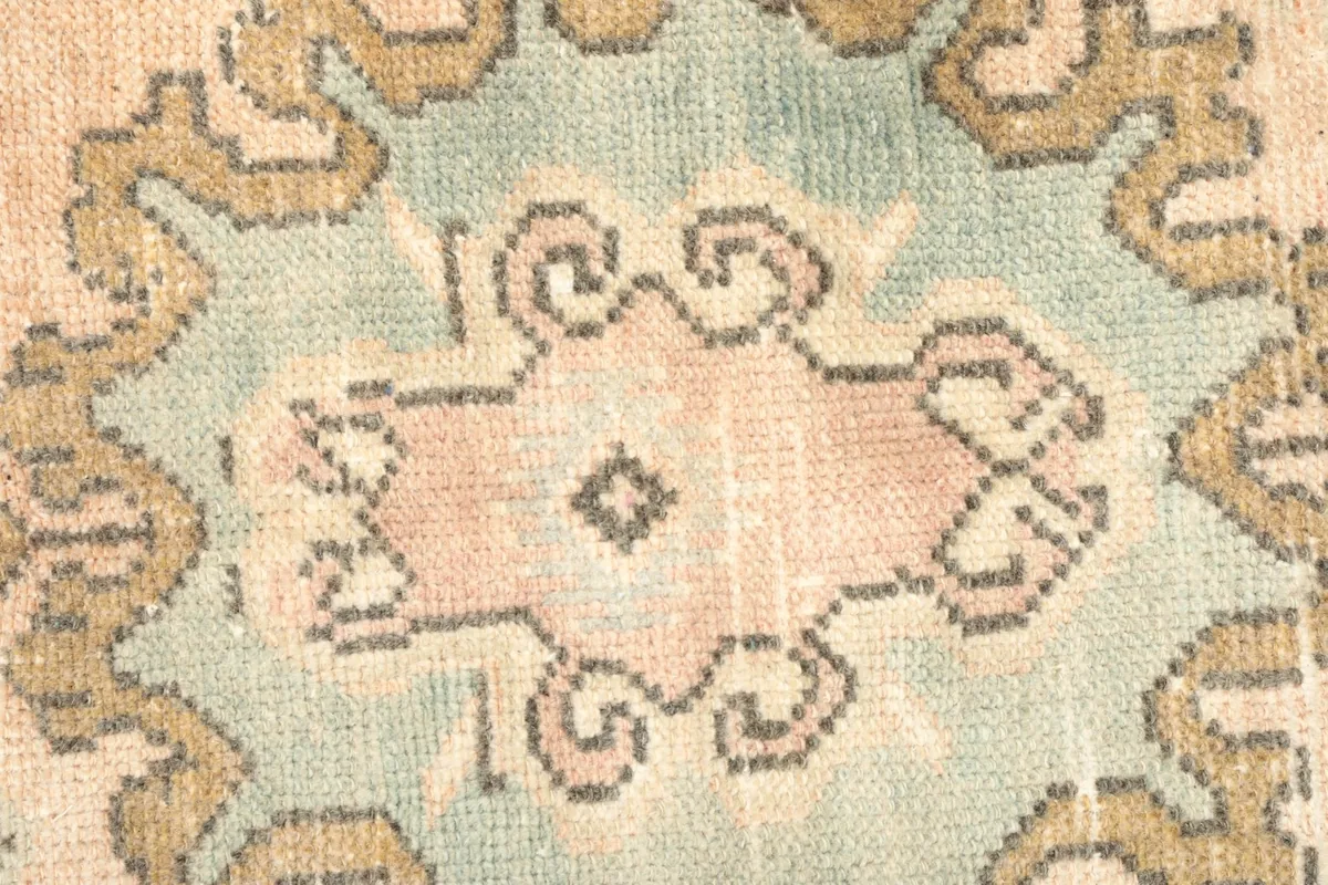 Very close detail of the blue and rose colors within the central medallion of the vintage rug.