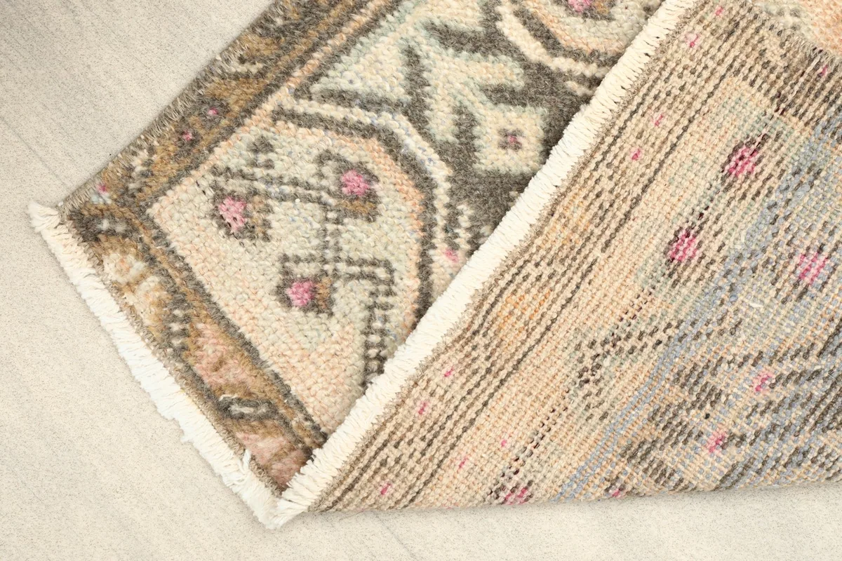 View of the rug folded to show the backing and the texture of the hand-knotted wool pile.