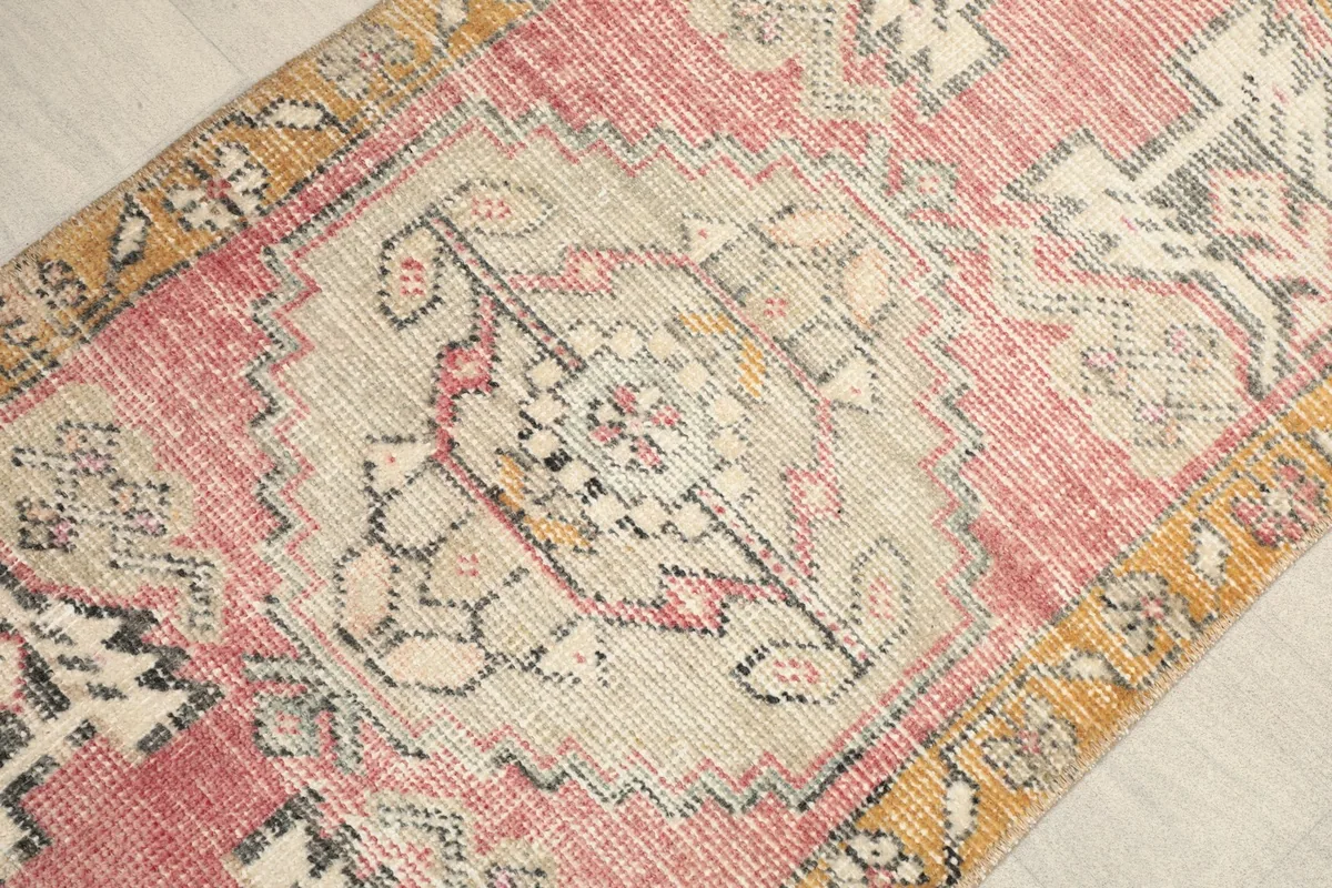 Angled view highlighting the central beige medallion and the faded rose and gold colors of the rug.