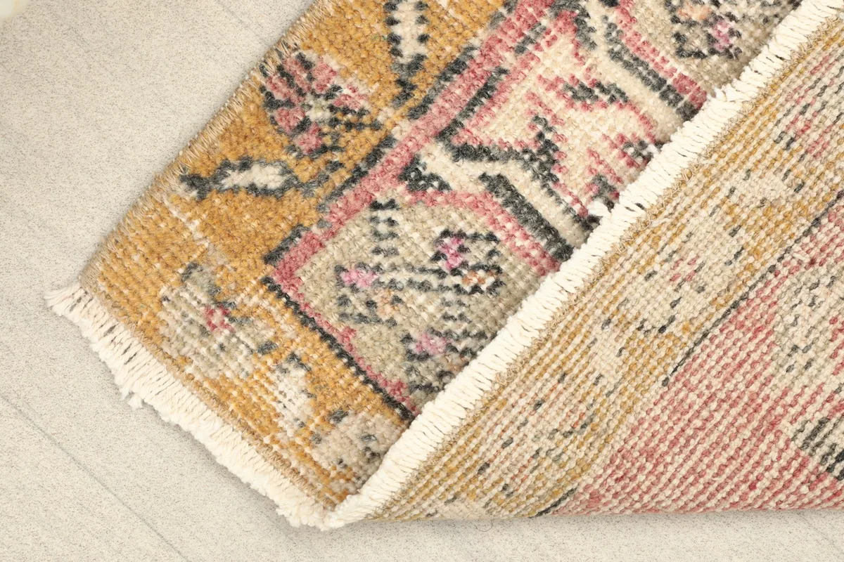 Rug corner folded back to reveal the wool pile and cotton foundation, showing the hand-knotted construction.