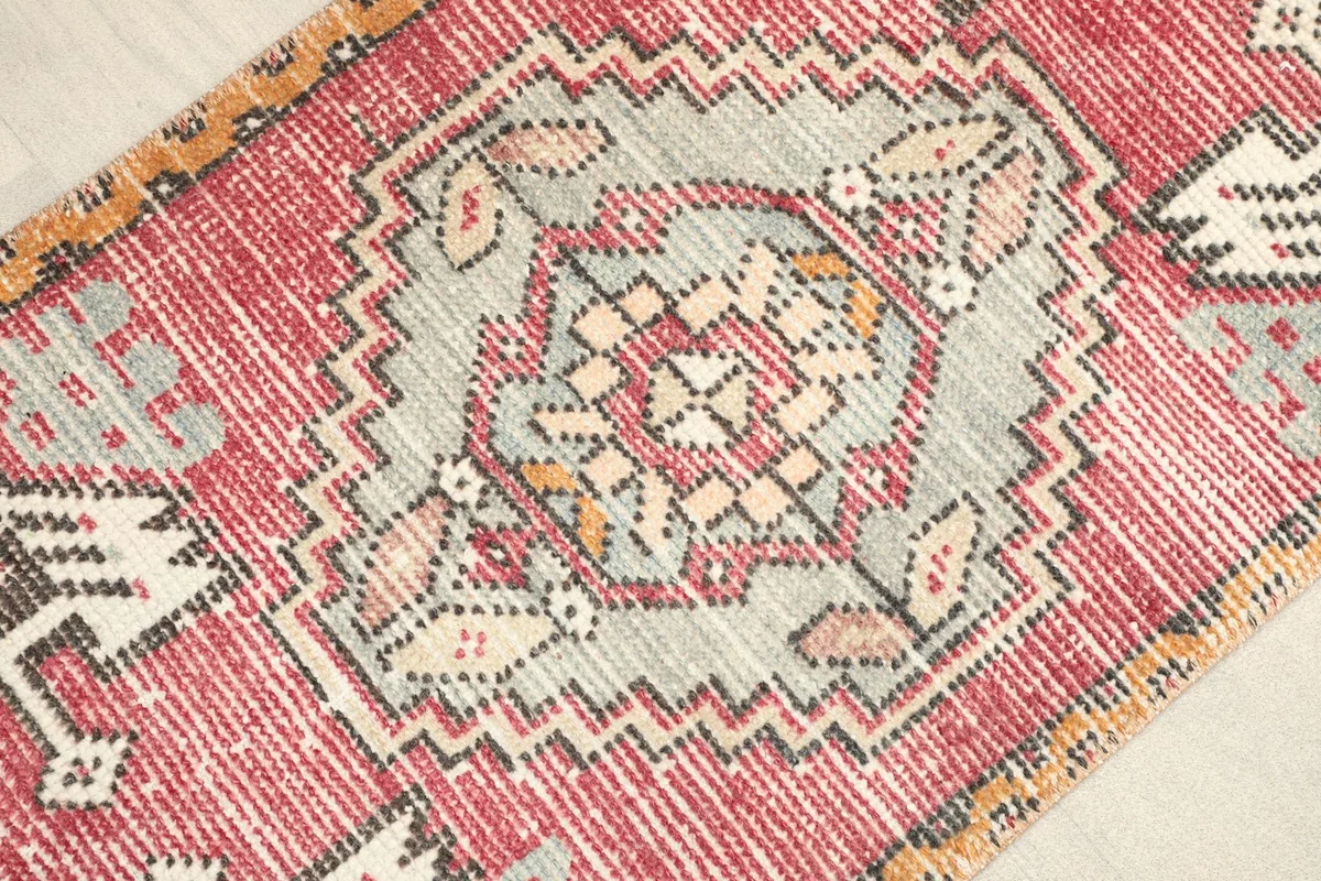 Close-up detail of the central gray medallion and surrounding geometric motifs in rose, gold, and cream.