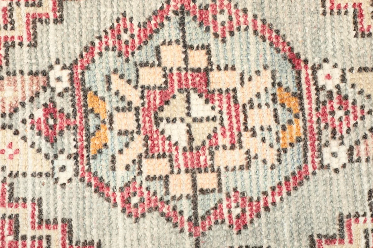 Detailed view of the intricate geometric patterns and color variations within the rug's medallion.