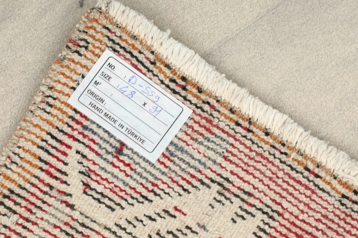 Back of the rug with a label, showing the cotton foundation and the neat rows of hand-knotted wool.