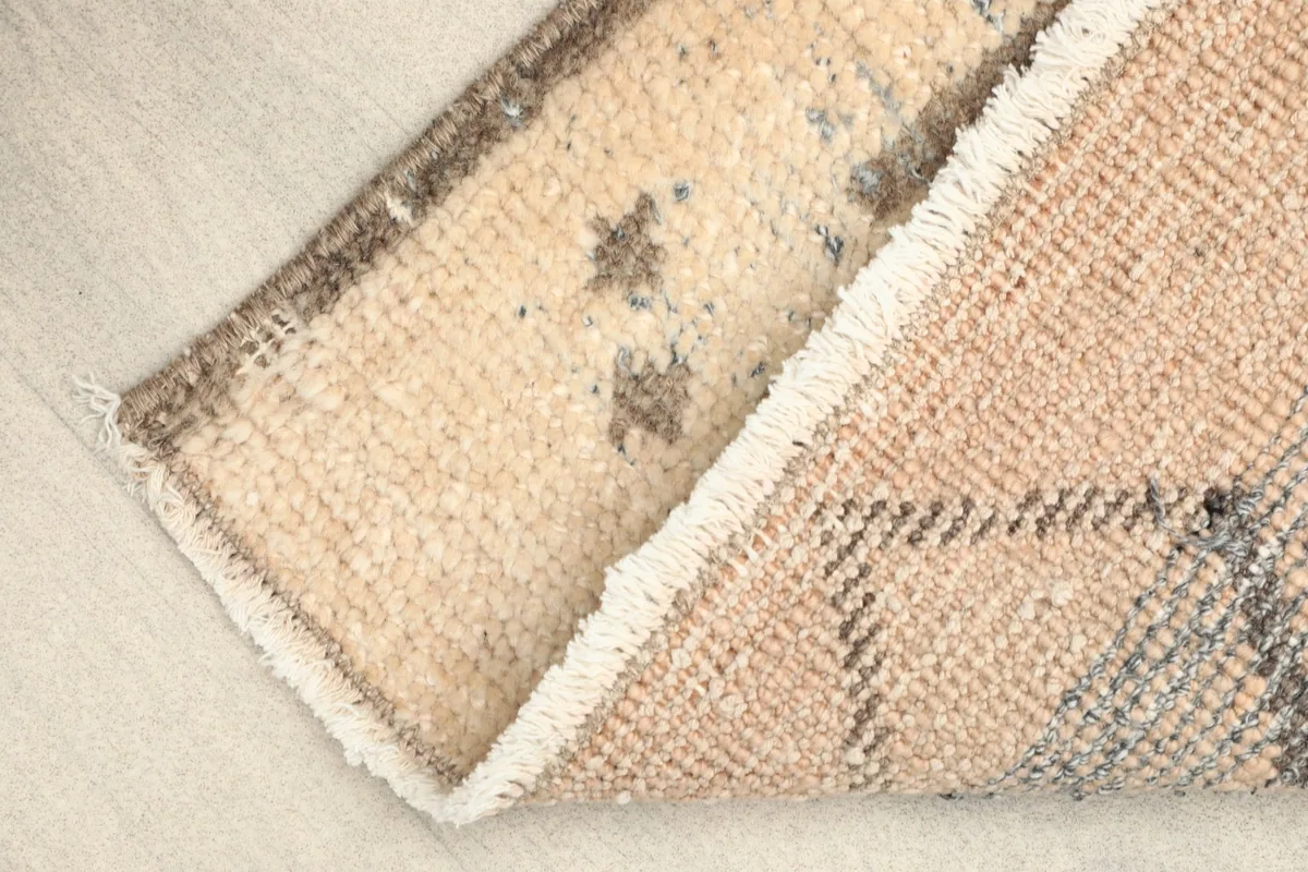 View of the rug's corner folded to show the cotton foundation and reverse side.