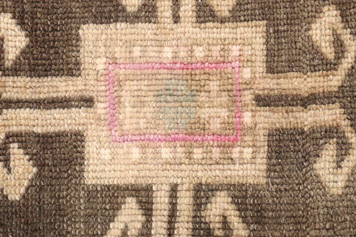Close-up detail of the central beige motif with pink and light blue accents.