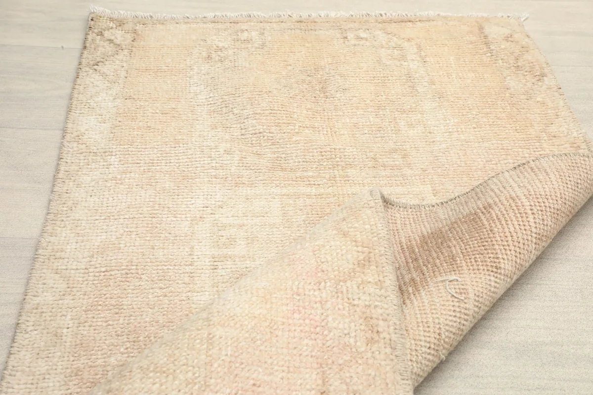 Angled view of the rug with a corner gently folded, emphasizing its texture and vintage appeal.