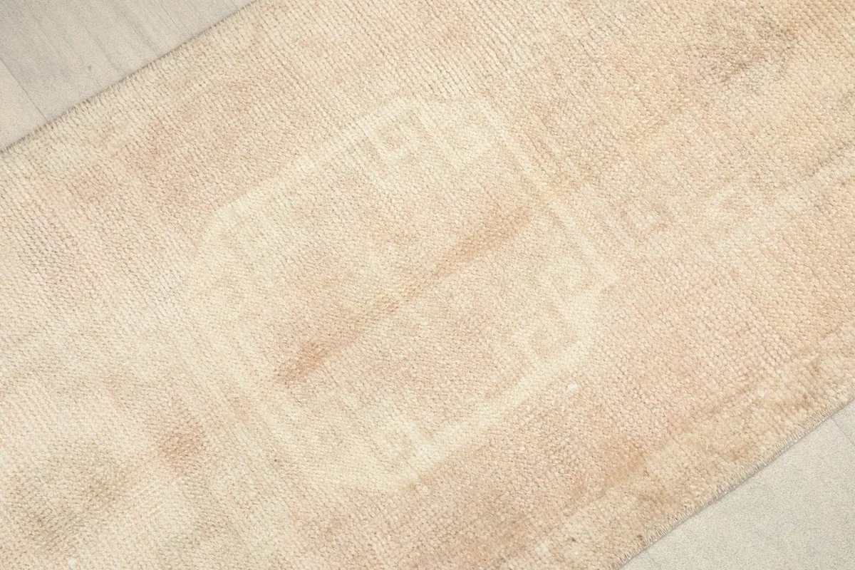 Close-up detail of the hand-knotted wool pile, revealing faded geometric motifs and natural wear.