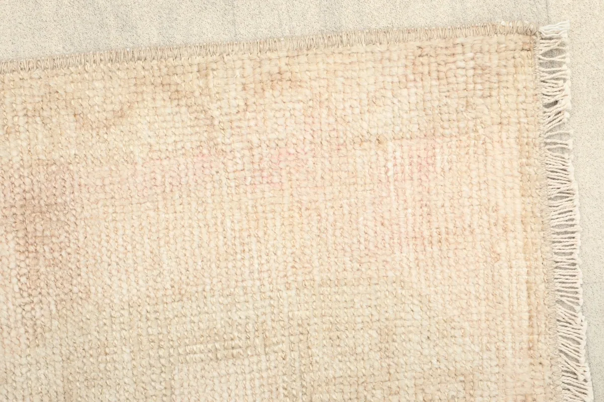 Close-up of the rug's edge, highlighting the vintage fringe and the intricate hand-knotting.