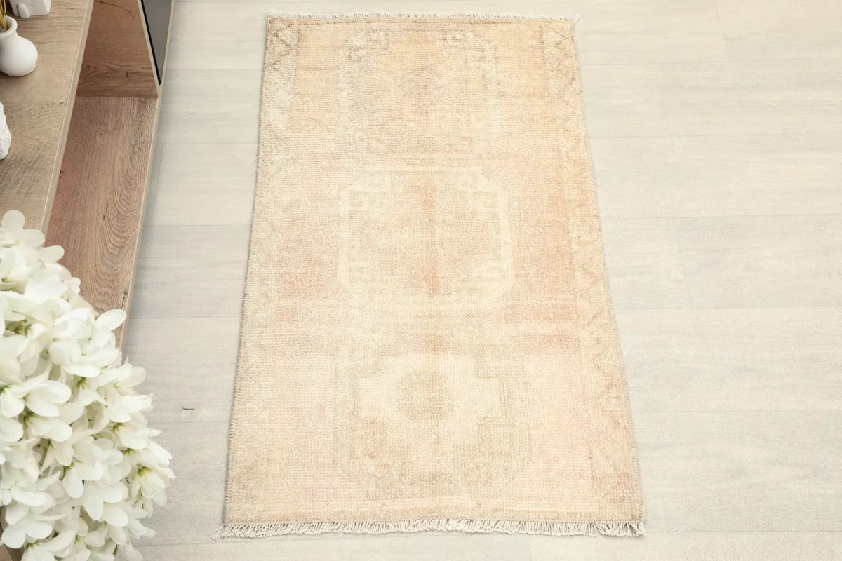 Overhead view of the vintage beige rug, showing its subtle geometric patterns and muted colors.