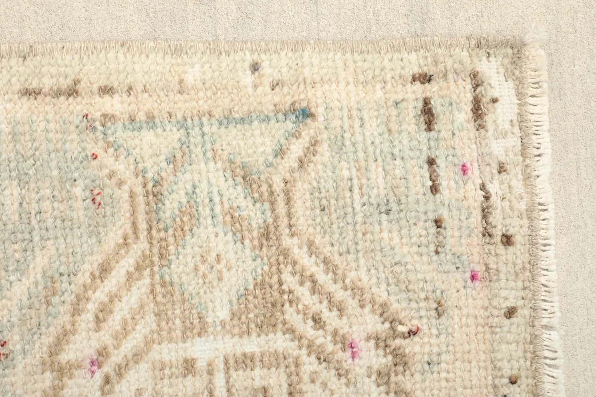 Detailed view of the geometric patterns and texture in the beige, green, and tan wool pile.