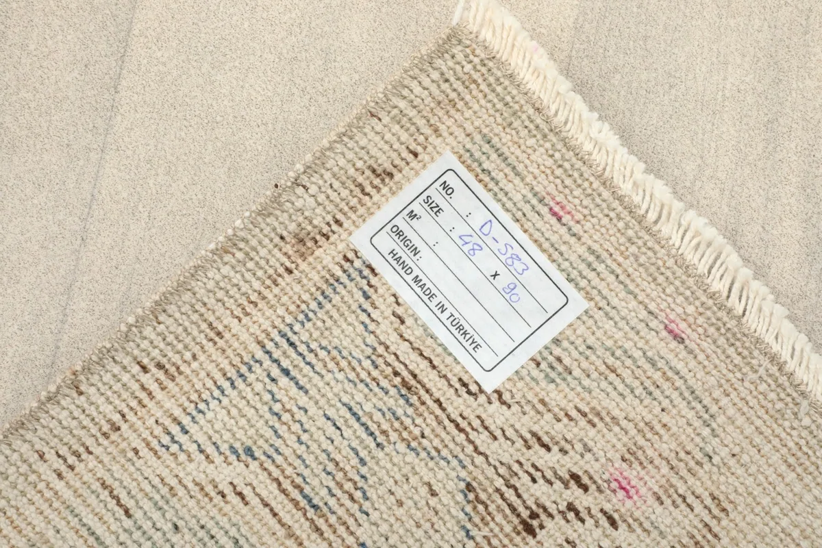Close-up of the rug's back, displaying the hand-knotted cotton foundation and a product label.