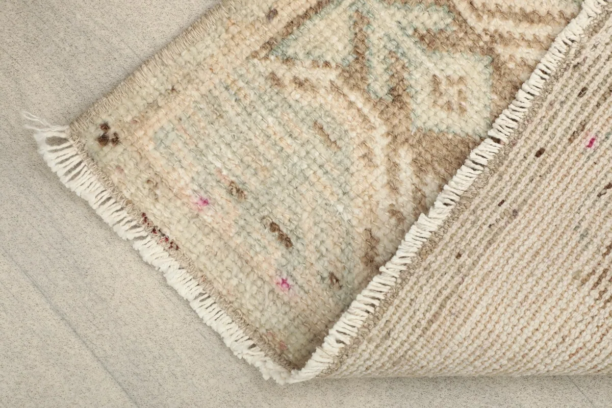Corner of the rug folded back to reveal the cotton foundation and the reverse side of the knots.