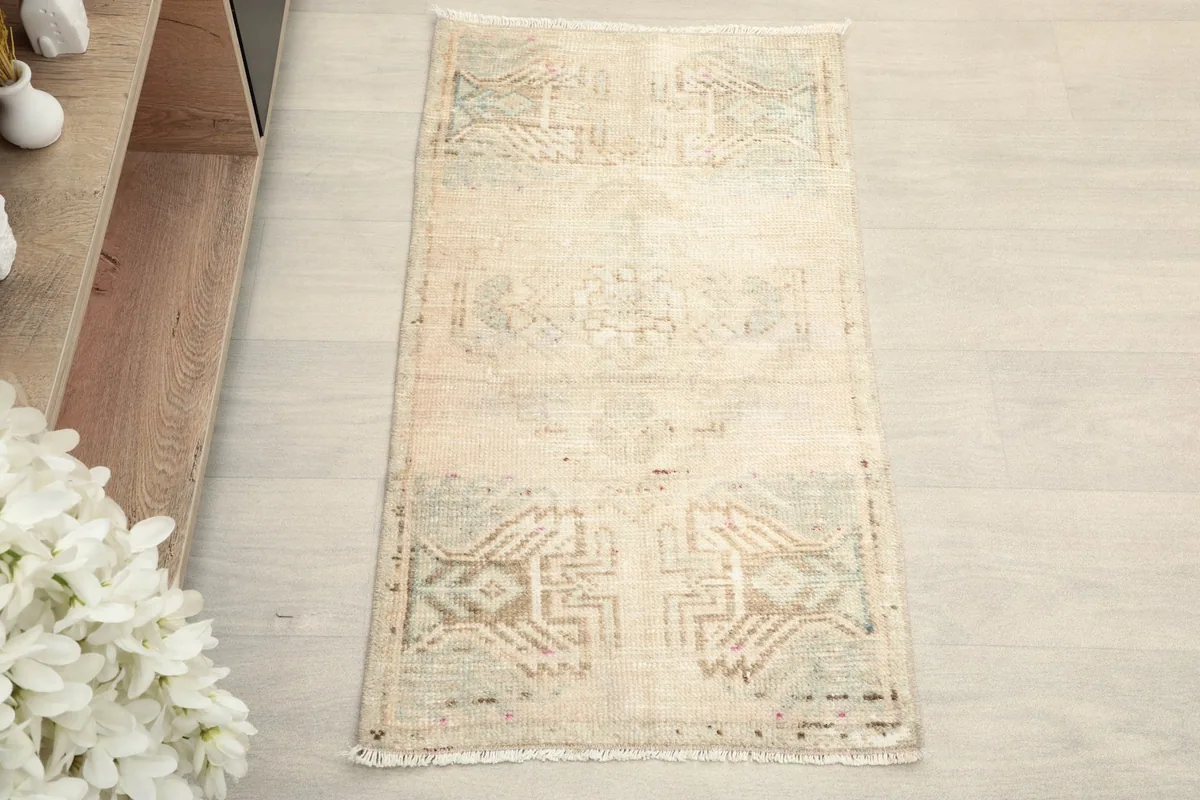 Overhead view of the beige vintage rug, showcasing its geometric patterns in green and tan.