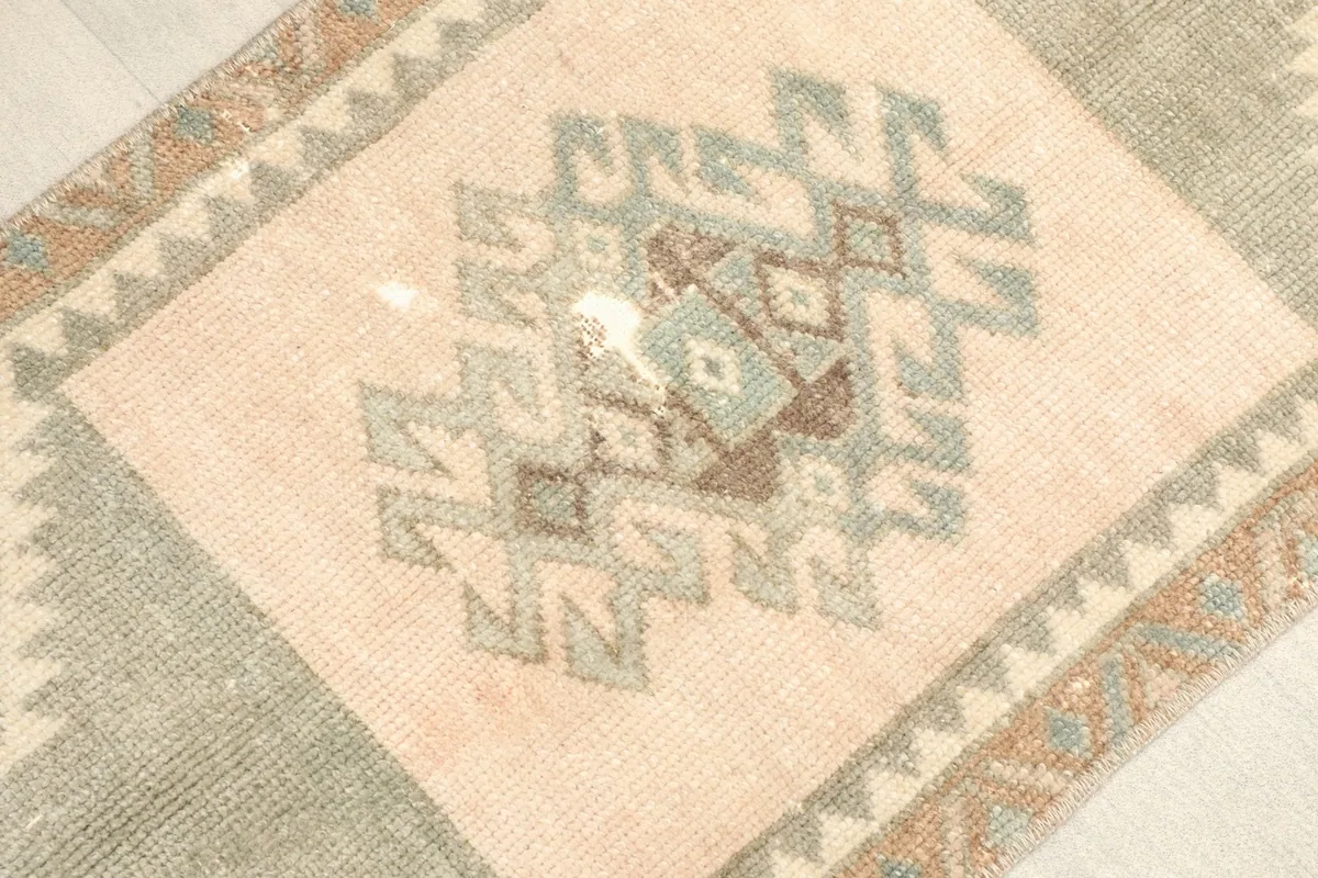 Close-up of the central geometric motif showing green, beige, and rust colors